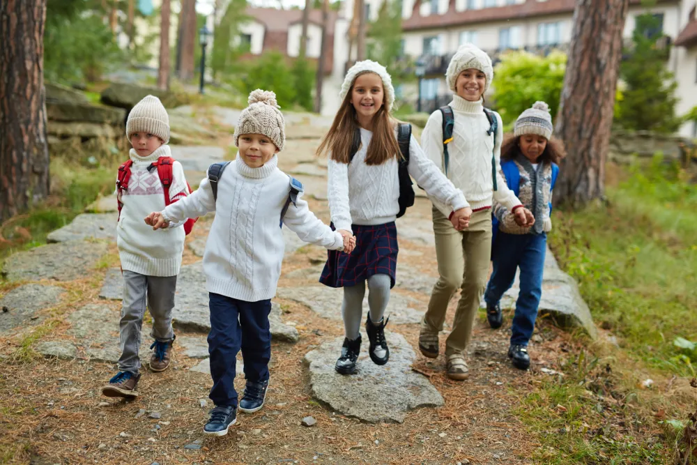 Fröhliche Kinder mit Schulranzen laufen nach der Schule ins Freie