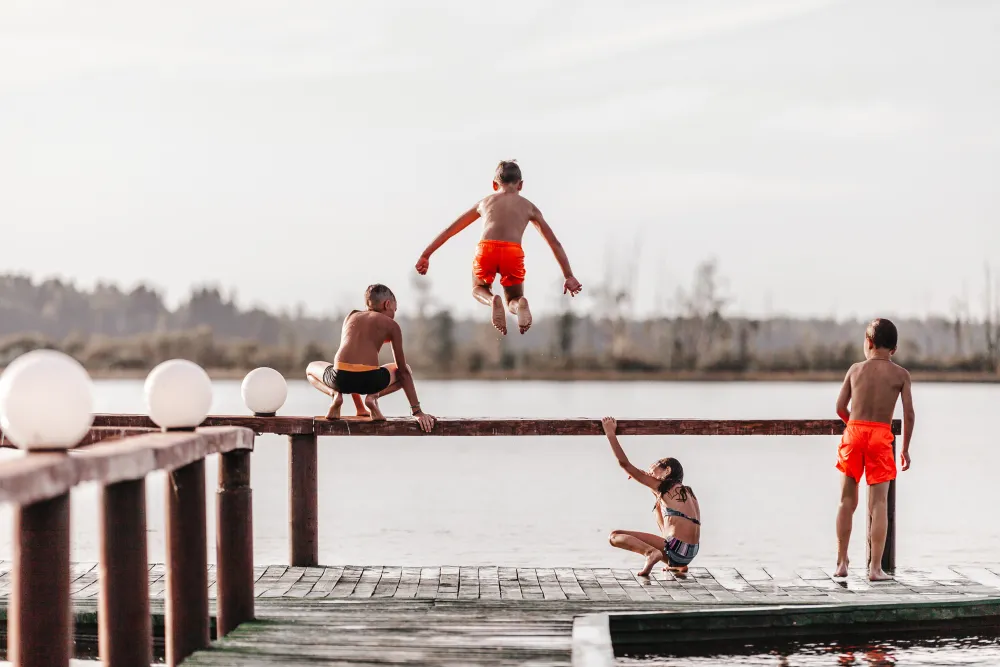 Kinder in Badekleidung springen im Sommer ins Wasser